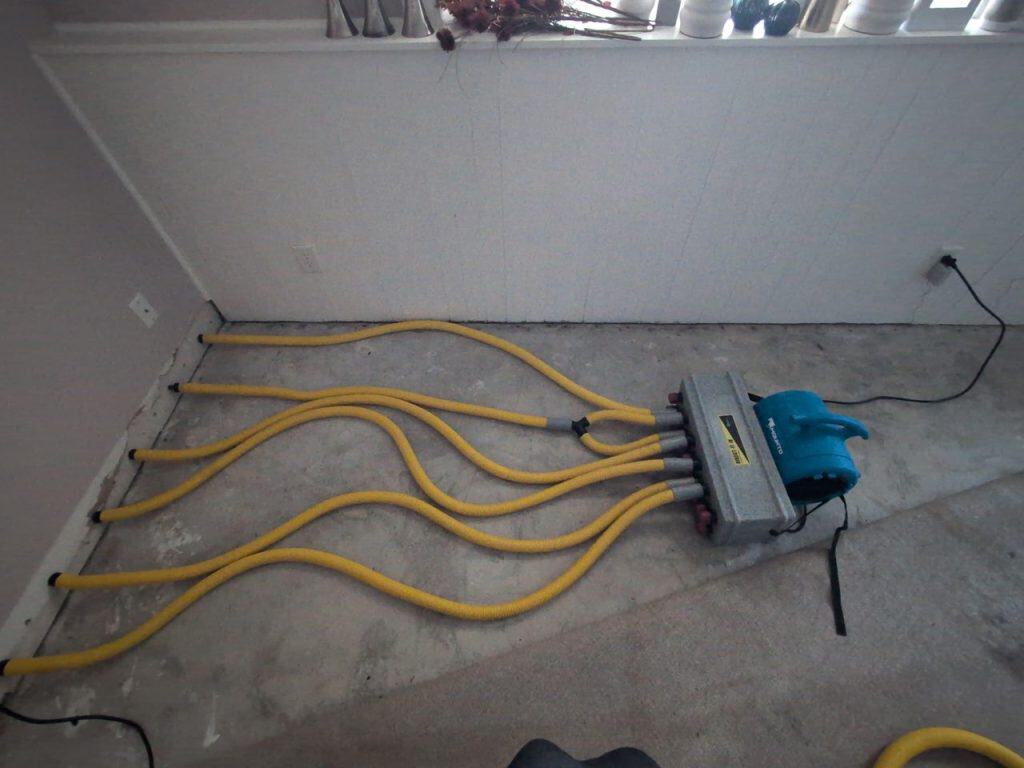Water extraction machine with hoses on a concrete floor during cleanup.