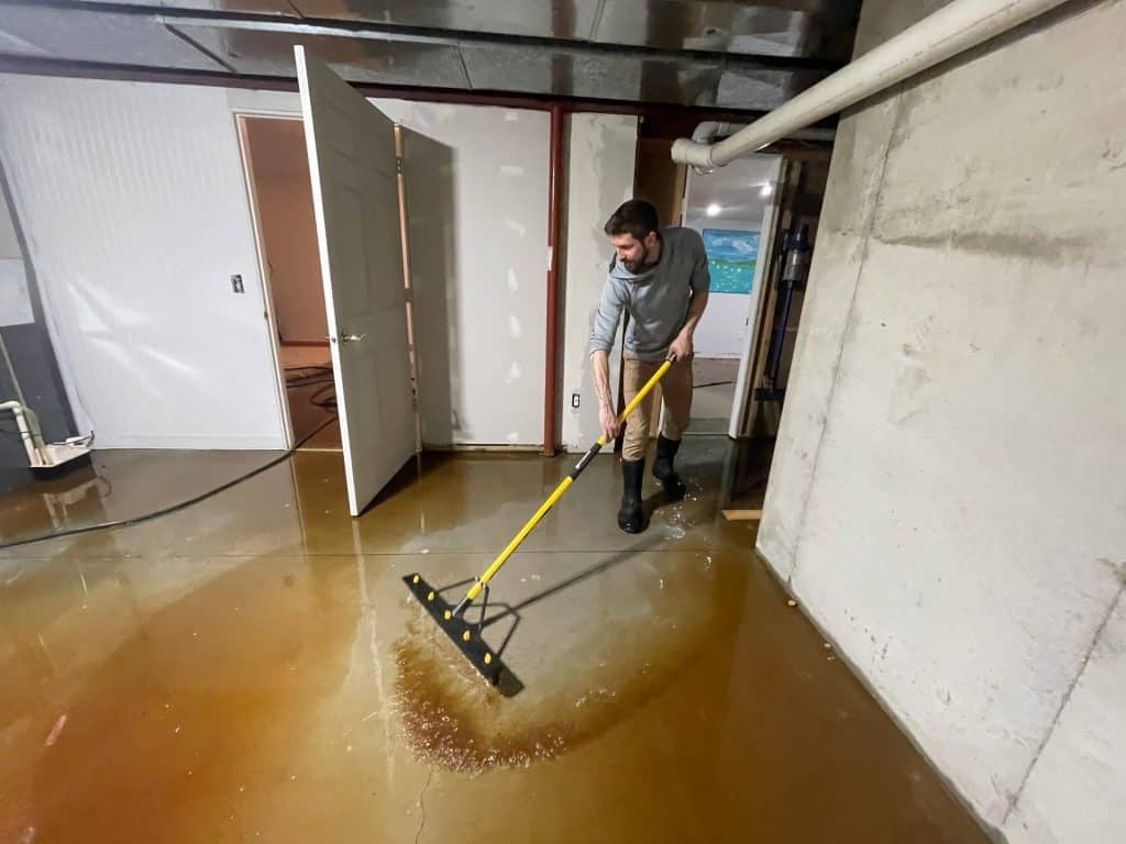 Technician performing water extraction on flooded floor in commercial space.