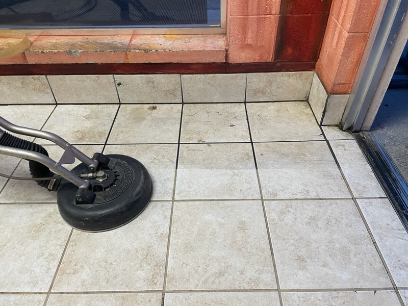 Professional tile and grout cleaning at entrance with cleaning machine.