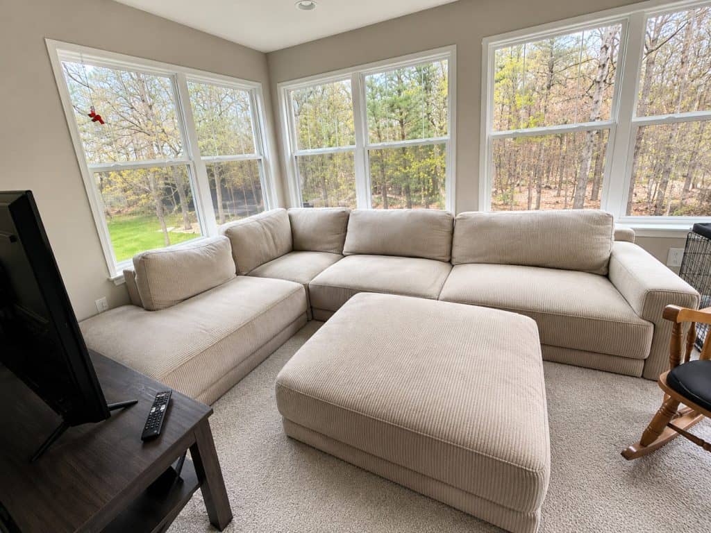 Clean beige sectional sofa in sunlit living room after cleaning.
