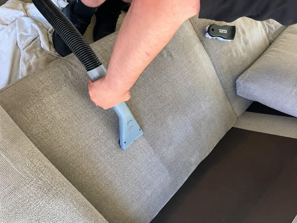 Cleaning a fabric sofa with a professional vacuum for deep stain removal.