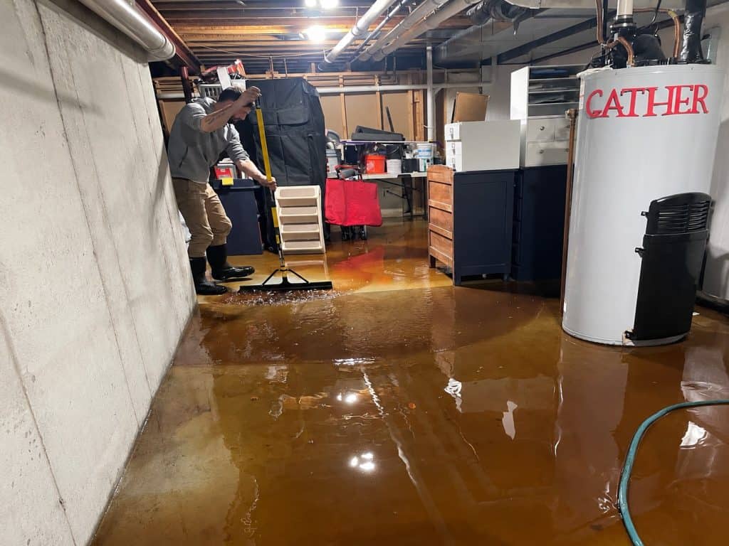 Water extraction process in basement with professional equipment and workers.