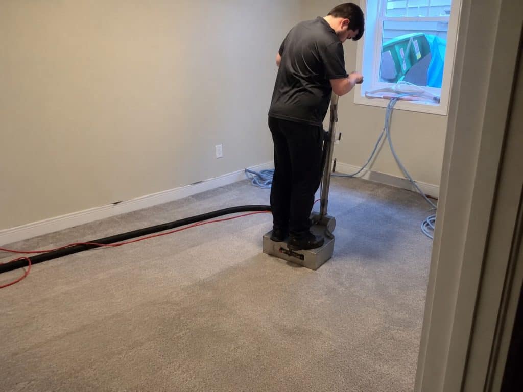 Technician performing water extraction on carpet after flooding or spill.