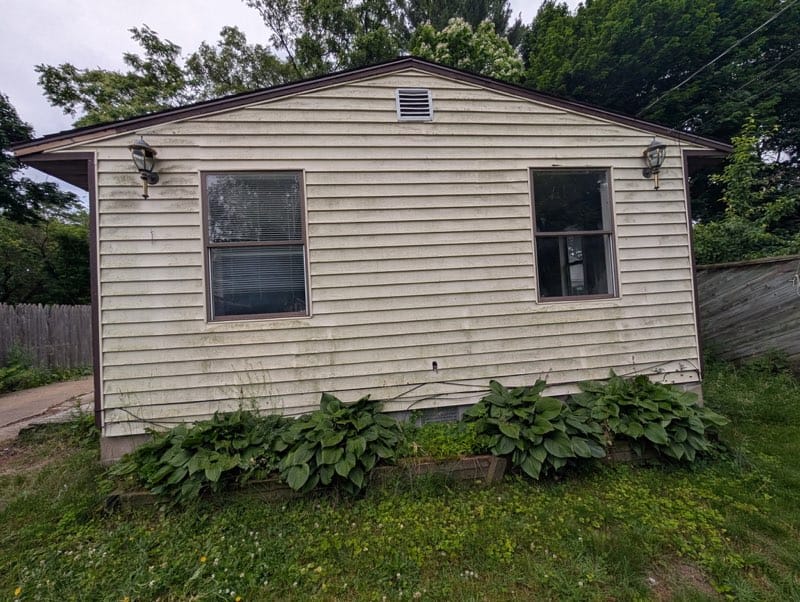 House exterior before power washing showing dirt and grime buildup.