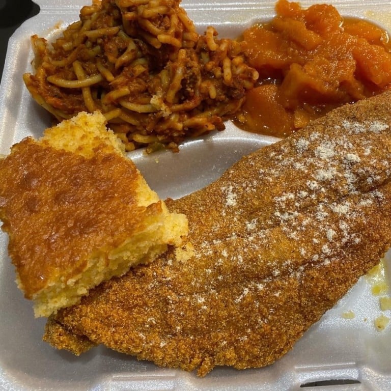 Crispy fried catfish fillet served with seasoned rice, sweet potato casserole, and collard greens, highlighting Southern soul food cuisine.