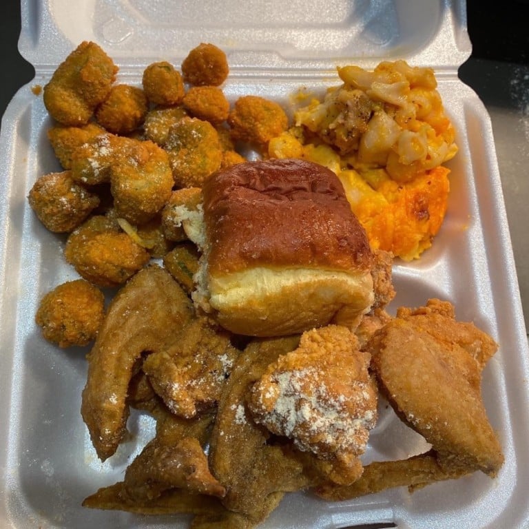 Delicious crispy chicken wings with sides of fried okra, macaroni and cheese, and mashed potatoes in a takeout container.