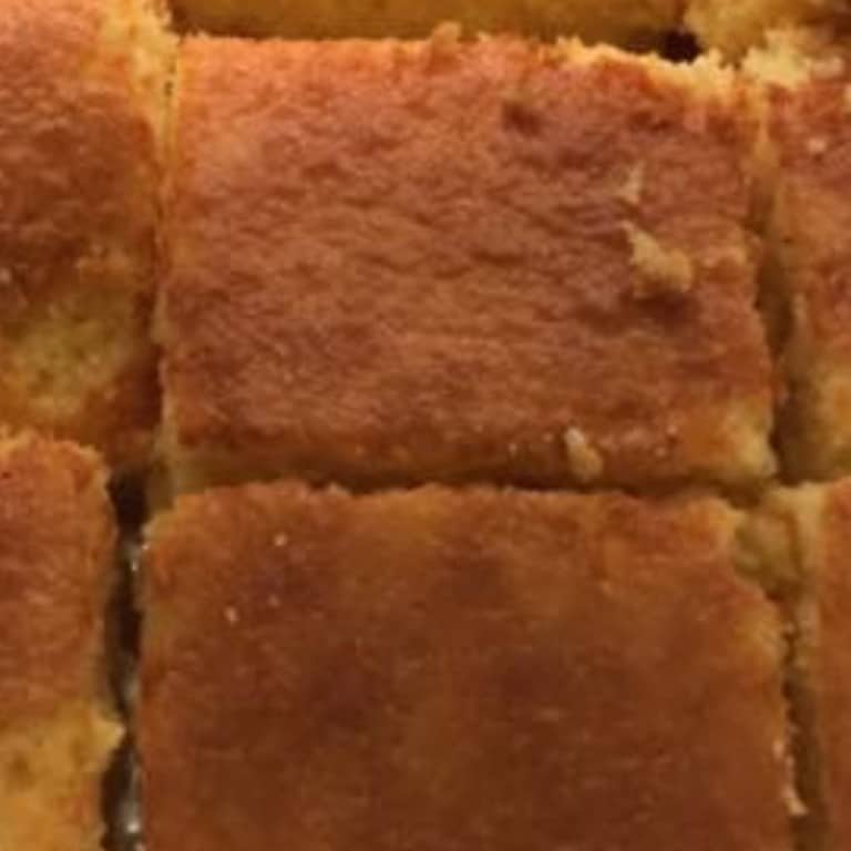 Close-up of golden-brown cornbread squares, freshly baked and crispy on the edges.