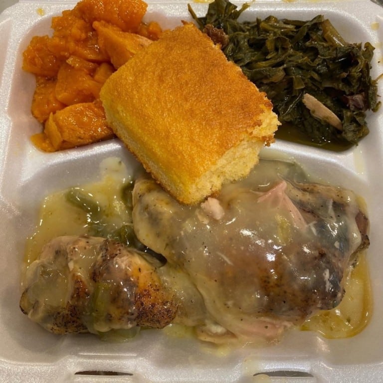 Delicious smothered chicken leg quarter served with cornbread, collard greens, and sweet potatoes, highlighting Southern soul food cuisine. Perfect for comfort food lovers.