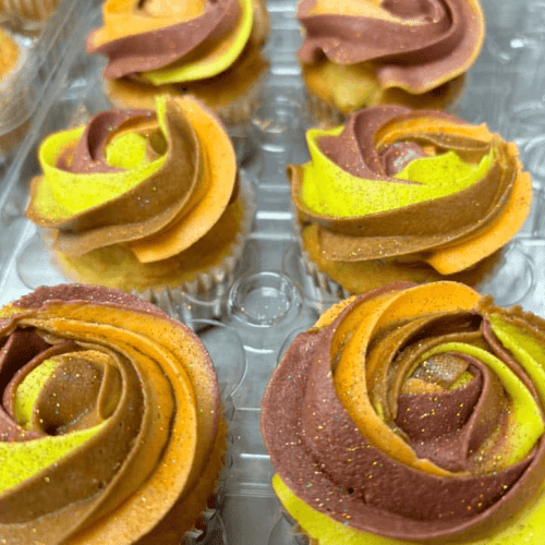 Delicious swirl cupcakes with vibrant yellow and chocolate frosting, perfect for any celebration. Freshly baked with rich flavors and eye-catching presentation.