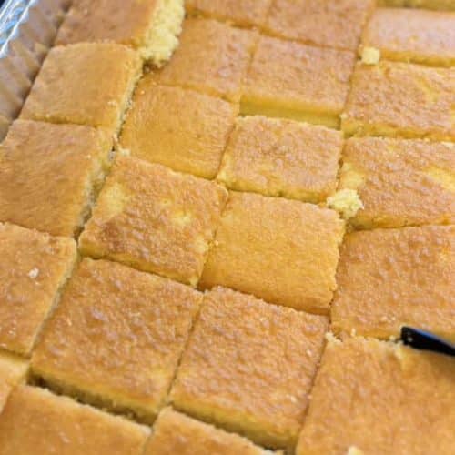 Freshly baked cornbread cut into squares, golden brown crust with soft interior, served in a catering tray. Perfect for Southern comfort food and gatherings.