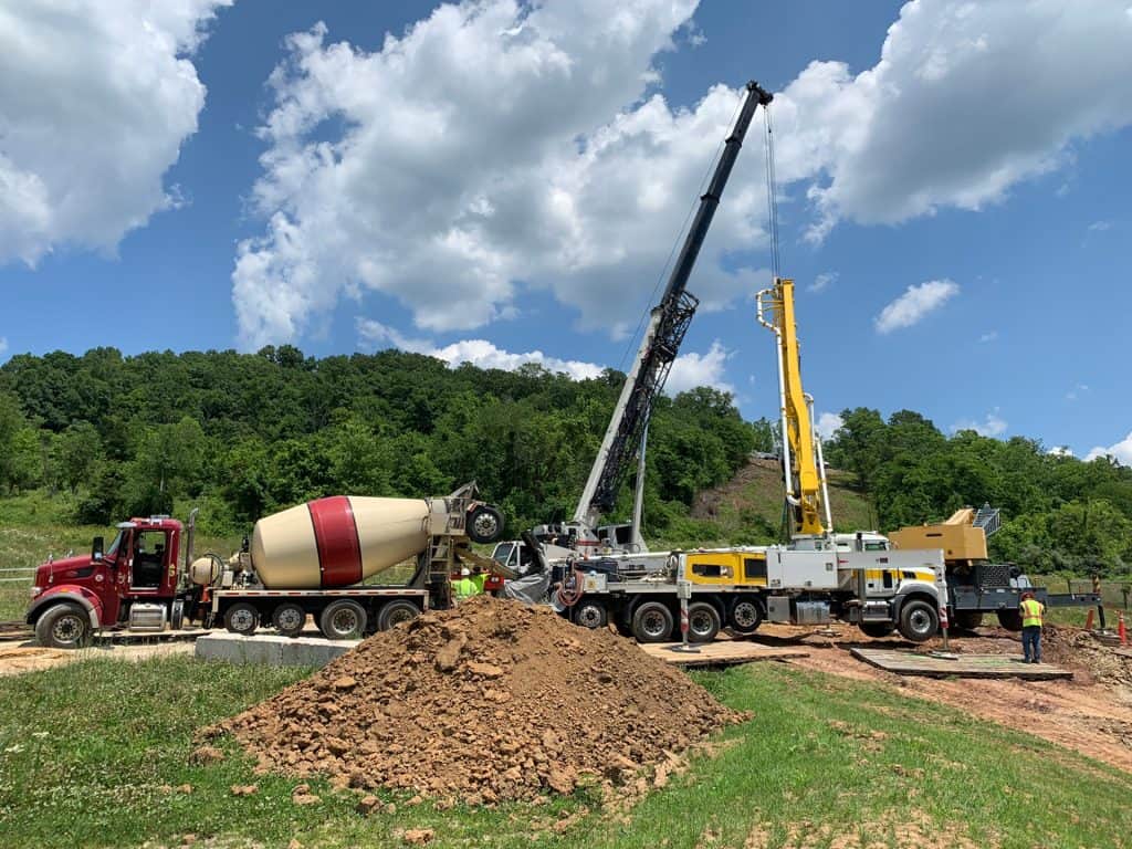 Heavy construction equipment including a concrete mixer truck and cranes working on site.