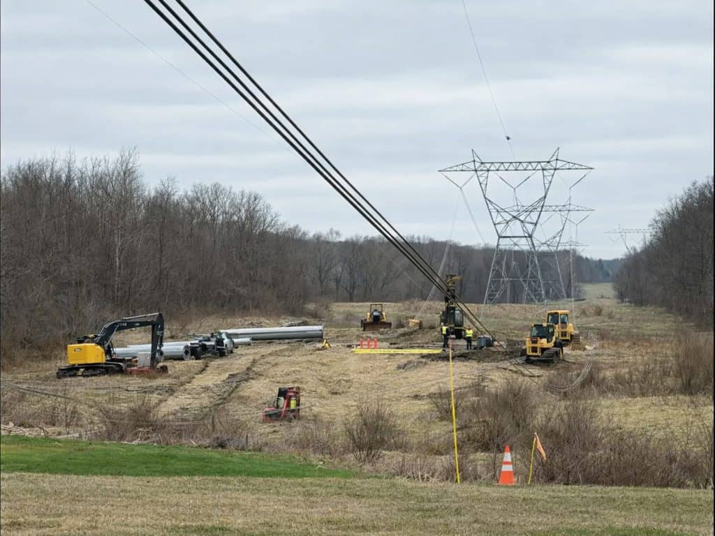 Power line repair work after storm damage at 765kV transmission tower site.