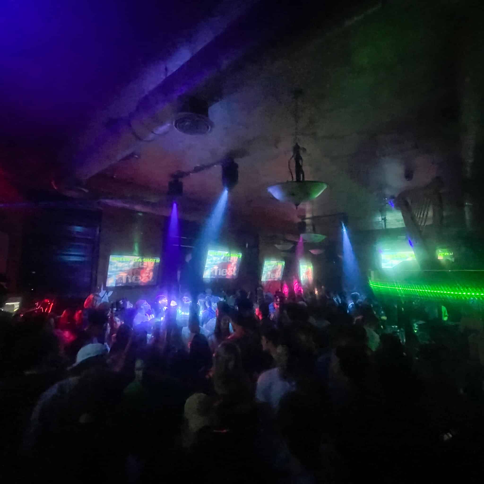 Crowd enjoying nightlife at Dublin Square with colorful lights and screens.