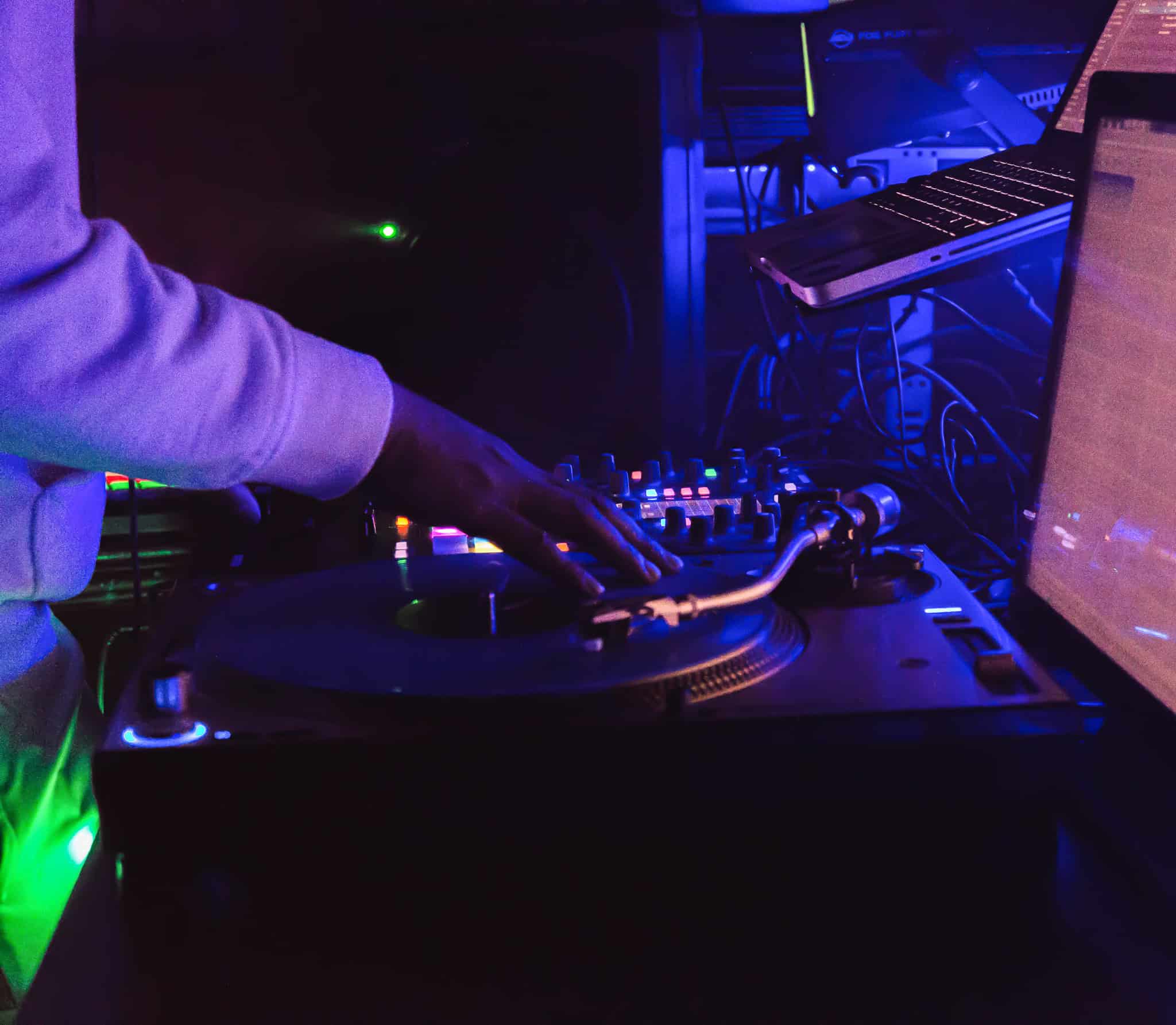 DJ mixing music at Dublin Square with turntables and laptop in a dimly lit setting.