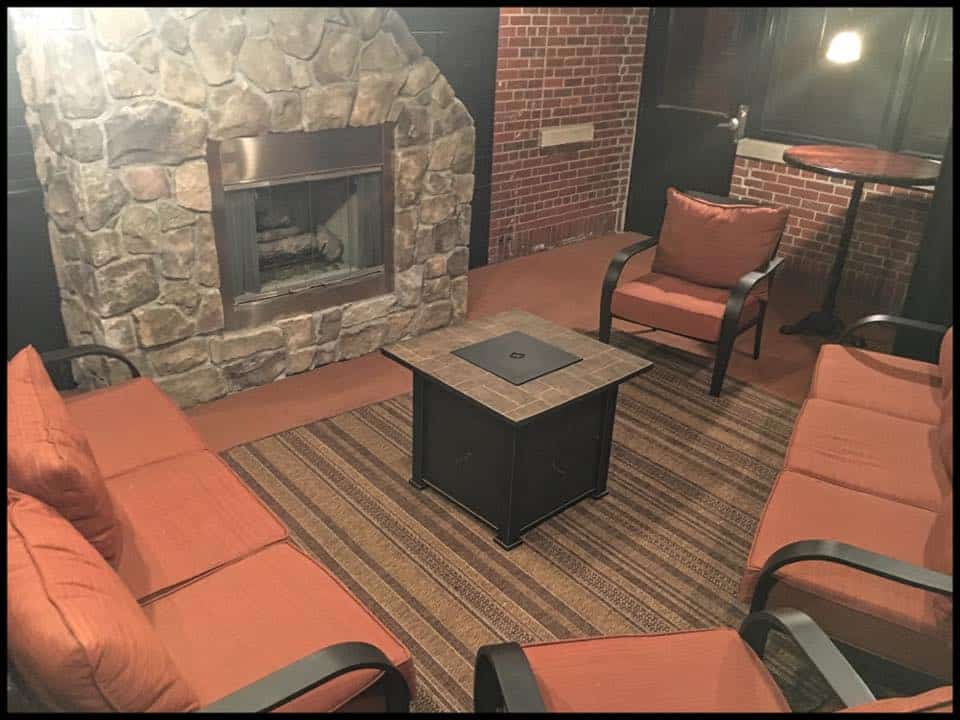 Cozy lounge with brick fireplace and comfortable seating at Dublin Square.
