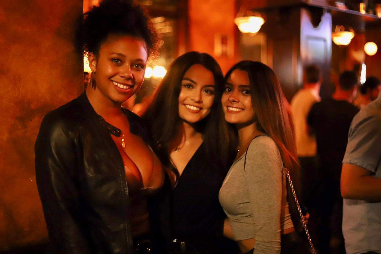Three women smiling at Dublin Square bar in Lansing, Michigan.