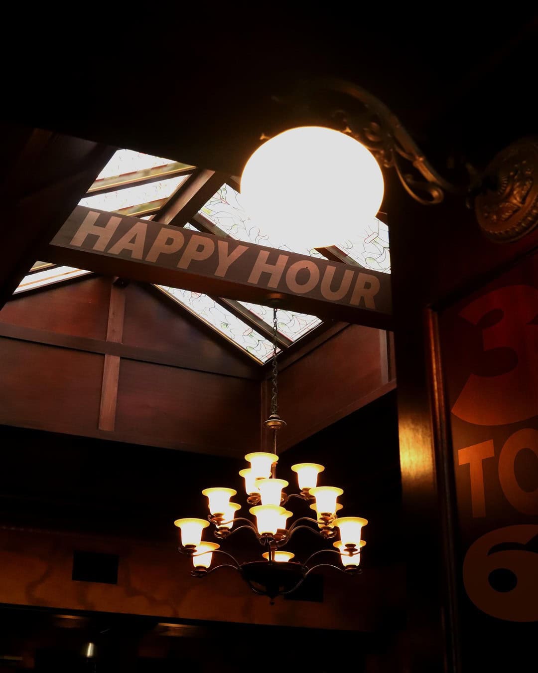 Interior view of Dublin Square with happy hour sign and chandelier lighting.