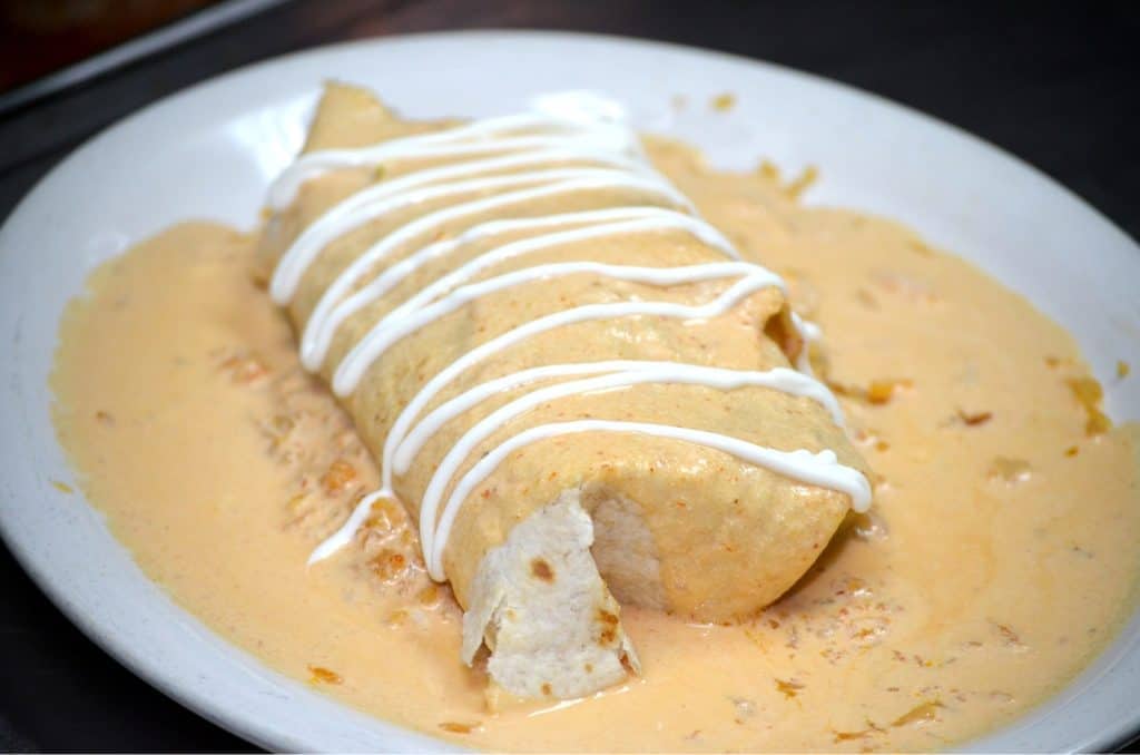 Delicious Mexican burrito served with creamy sauce and drizzle. Perfect for catering events and gath.