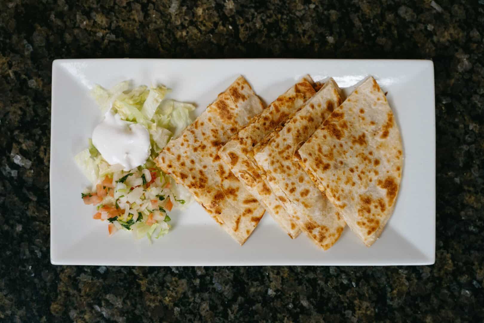 Cheese quesadillas served with lettuce and sour cream at El Burrito Loco.