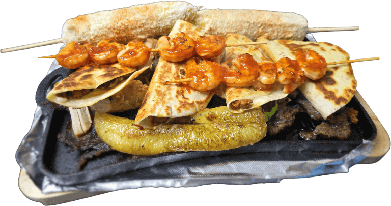 Assorted Mexican dishes including grilled shrimp, chicken, and vegetables on a sizzling platter.