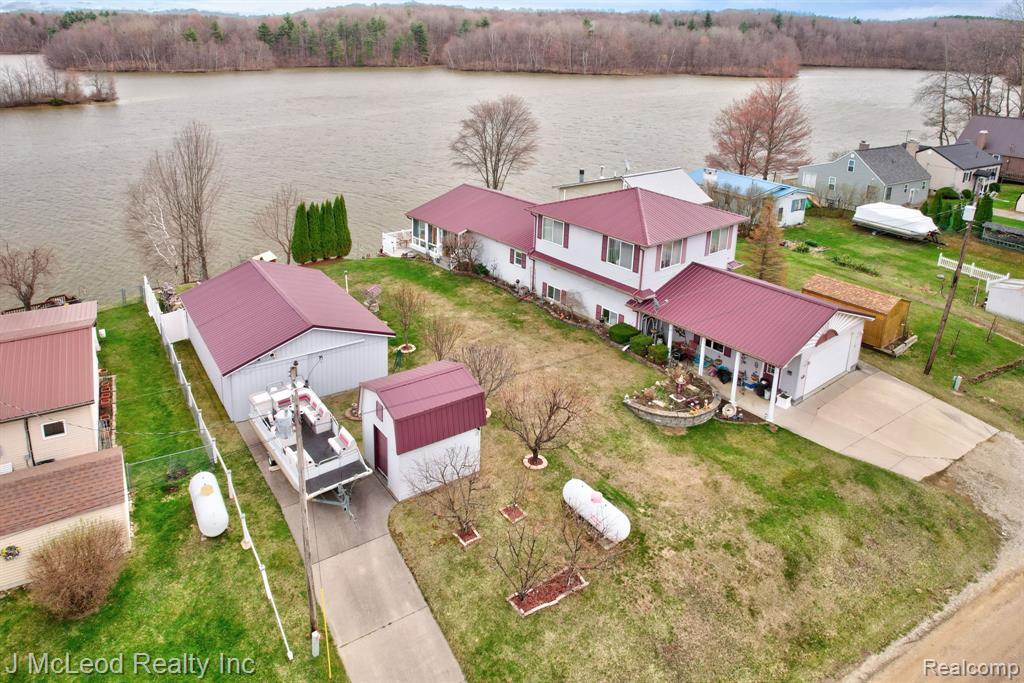 Welcome to lake life at its finest on beautiful Murphy Lake! This spacious waterfront home boasts over 100 feet of frontage on one of the most pristine and sought-after stretches of the lake, offering stunning panoramic views of the widest part of the water. Situated on three lots totaling .33 acres (110x132), this property provides exceptional space and functionality. The exterior is designed for ultimate lakefront enjoyment with a professionally tiered yard, cement paver steps, and an impressive retaining wall leading to Trex decking and steps down to the water. The final tier features paved access to the shoreline, where an aluminum dock is included. Multiple outbuildings offer abundant storage, including a 30x23 pole barn, 2.5 car garage, and three additional sheds—one lakeside shed equipped with electricity and a beverage refrigerator, perfect for entertaining. Inside, you’ll find an open-concept kitchen, dining, and living area ideal for gatherings, along with a main floor bedroom and full bath. A stunning 12x34 four-season room with expansive lake views features a hot tub for year-round relaxation. Upstairs offers a large landing/family room, two additional bedrooms, and a full bath. Adding even more versatility, a portion of the garage has been converted into a private in-law suite complete with a studio-style living space, kitchen, full bath, and laundry—perfect for guests or extended family. Additional highlights include all appliances included, newer windows throughout, and a durable metal roof. Two paved driveways provide convenient access to both the garage and pole barn. Murphy Lake is known for its size, beauty, and recreational opportunities, making it a premier destination for boating, fishing & relaxing lake days. Located in the charming and quaint town of Millington, you’ll enjoy a peaceful rural setting with small-town charm, while still being just 1–2 hours from Detroit—giving you that sought-after “up north” feel without the long drive.