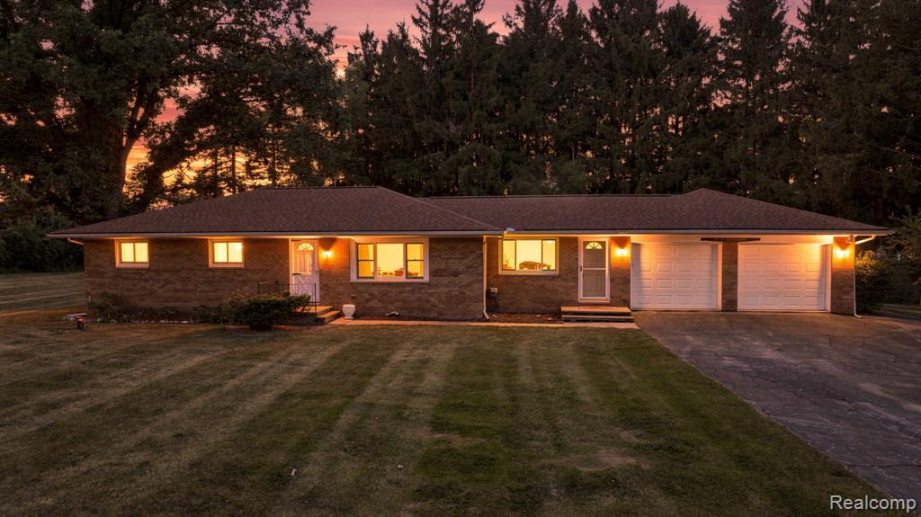 Brick exterior with a brown shingle roof, attached two-car garage, and a lush green lawn