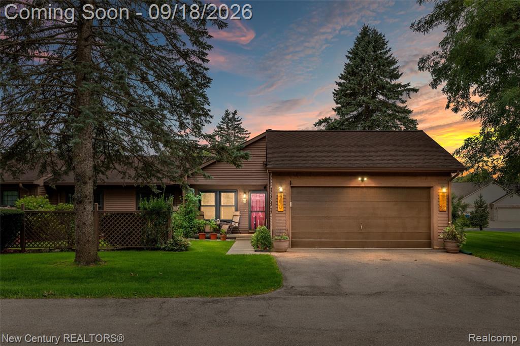 Siding exterior with an attached garage, a paved driveway, and mature landscaping