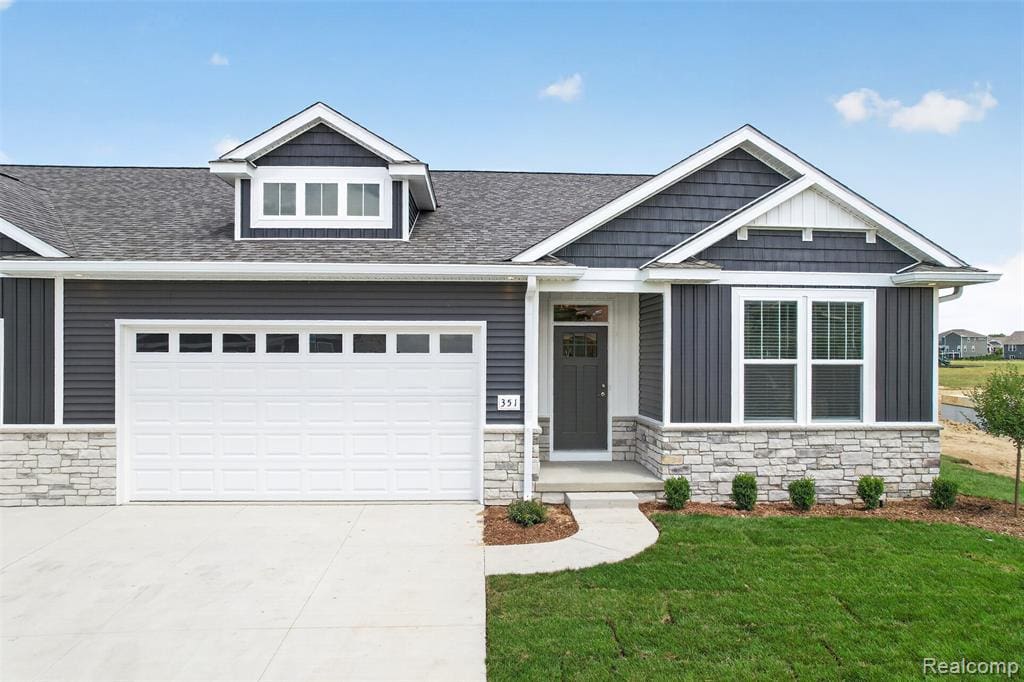 Modern exterior featuring dark gray siding with white trim accents and a partial stone facade