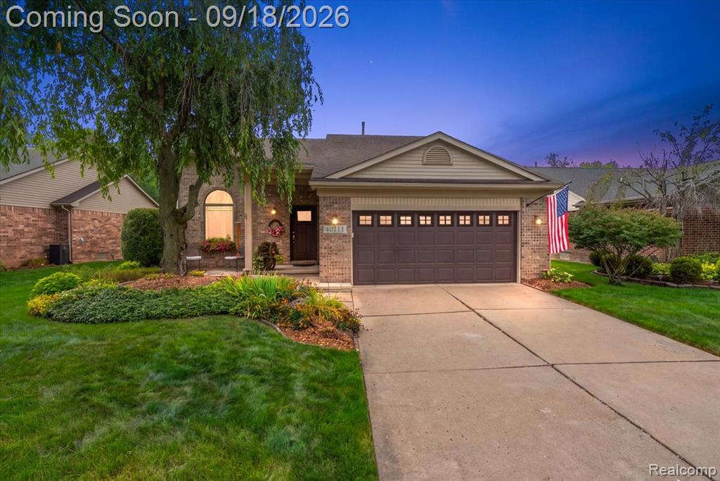 Brick exterior with a gabled roofline, concrete driveway, and attached garage