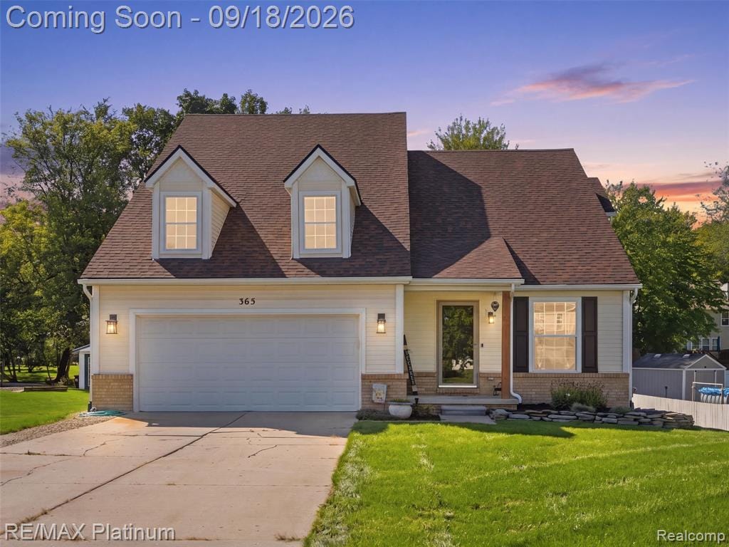 Light yellow siding with dormer windows, attached garage, stone accents, and a covered entry
