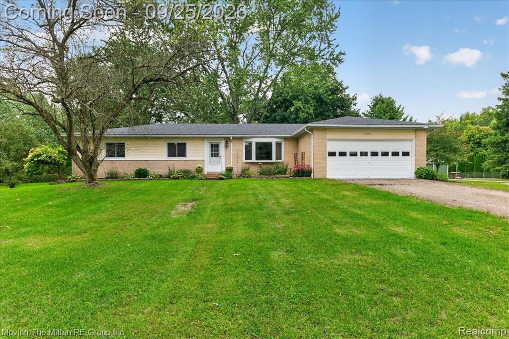 Ranch-style exterior with a light-toned brick and siding facade, attached garage, bow window, and a gravel driveway