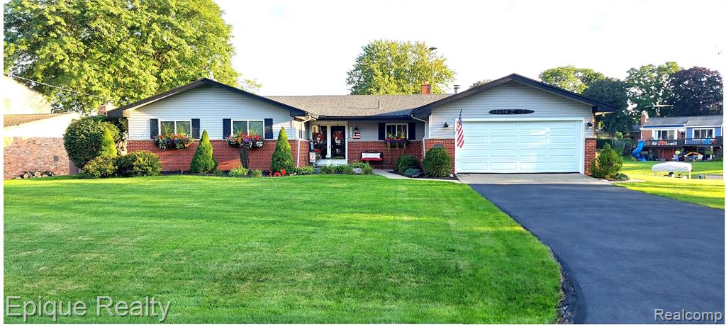 Ranch-style exterior with brick and siding, featuring a two-car garage and a paved driveway