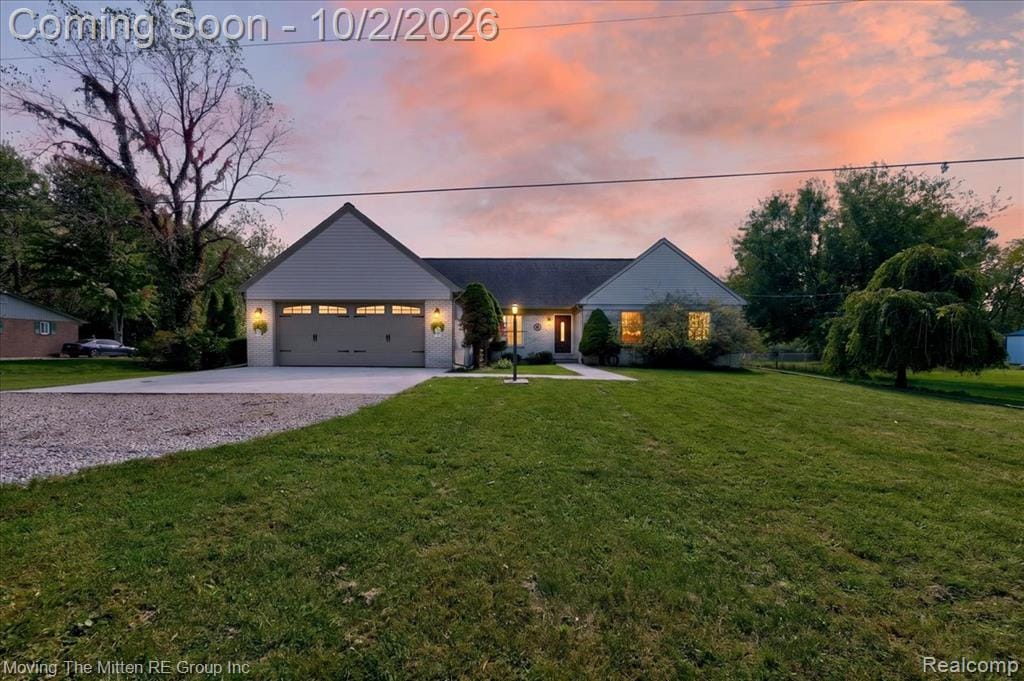 Gable roofline, attached two-car garage with arched window accents, gravel driveway, covered front entry, and exterior wall sconces