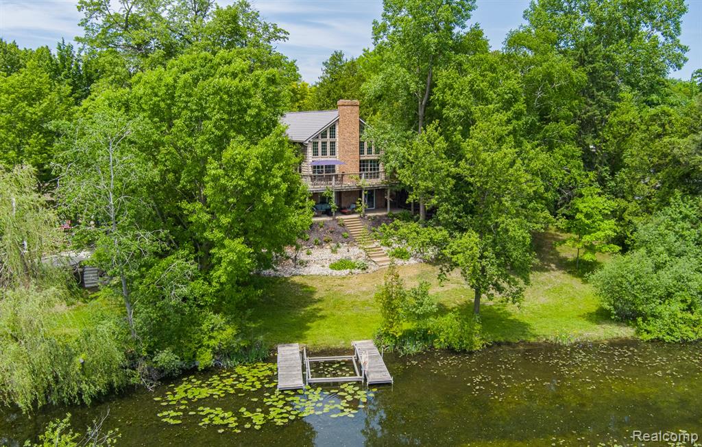 Welcome to this beautifully custom crafted home w/attention to detail t/out, located within 2 houses from main lake! A welcoming front entry sets the stage for this stunning home which opens to a bright flowing floor plan w/a sea of hardwood flooring and a cohesive neutral palette, designed for today's lifestyle. The impressive great room anchored by a classic marble fireplace, is highlighted by abundant natural light while providing serene water views, a seamless connection to the outdoors and wrap around decking. The heart of the home is the fully remodeled kitchen featuring extensive granite countertops, custom cabinetry, ss appliances and bar seating. The thoughtfully designed main level offers multiple living areas including a spacious dining area. The secondary floor primary suite is a true retreat, supersized sleeping and sitting areas, walk-in closet, ceramic bath w/euro style walk-in shower, jetted tub. The finished walkout lower level offers comparable quality to the principal living space with family room featuring yet another fireplace. 2 spacious bedrooms, full ceramic bath & loads of storage. Oversized 3 car garage (epoxy). Significant updates & extras: HVAC (2024), windows (2017), 3-dimensional vinyl cedar shake exterior (maintenace free), american metal roof (2010-100 yr warr), HWH (2014), multi-complex alarm & camera system, crank shore station, 2 docks. Outdoor living is equally impressive highlighted by fastidious landscaping. Ideally positioned within walking & biking distance to Downtown Clarkston, dining/shopping and corresponding schools, while offering quick access to I-75 for everyday convenience and commuting. NOTE: additional smaller piece of property available across the street from subject driveway, could be used as extra parking, storing water toys/boats ect. If interested will provide information!