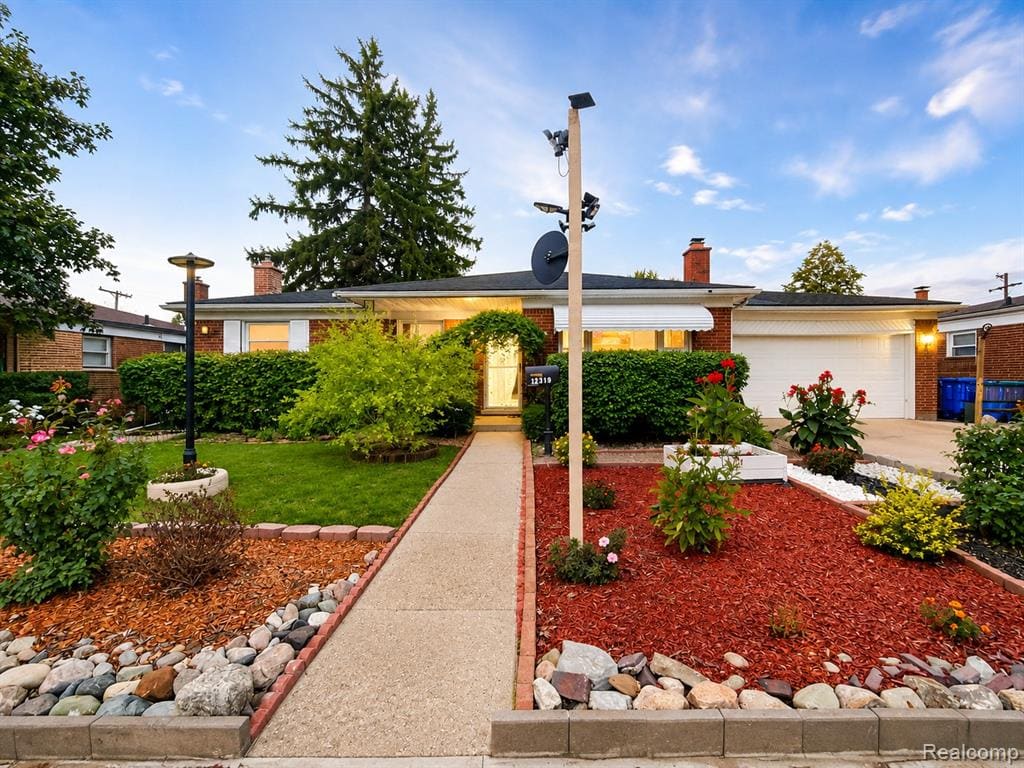 Brick facade, attached garage, concrete pathway, manicured lawn, and landscaped garden beds