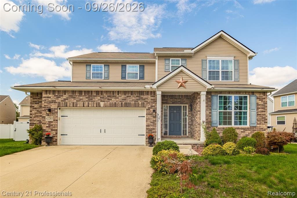 Brick and siding exterior with a covered entry, attached two-car garage, and established landscaping