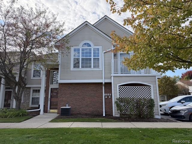 Siding exterior with brick detailing, arched transom window, upper-level balcony, and a manicured lawn