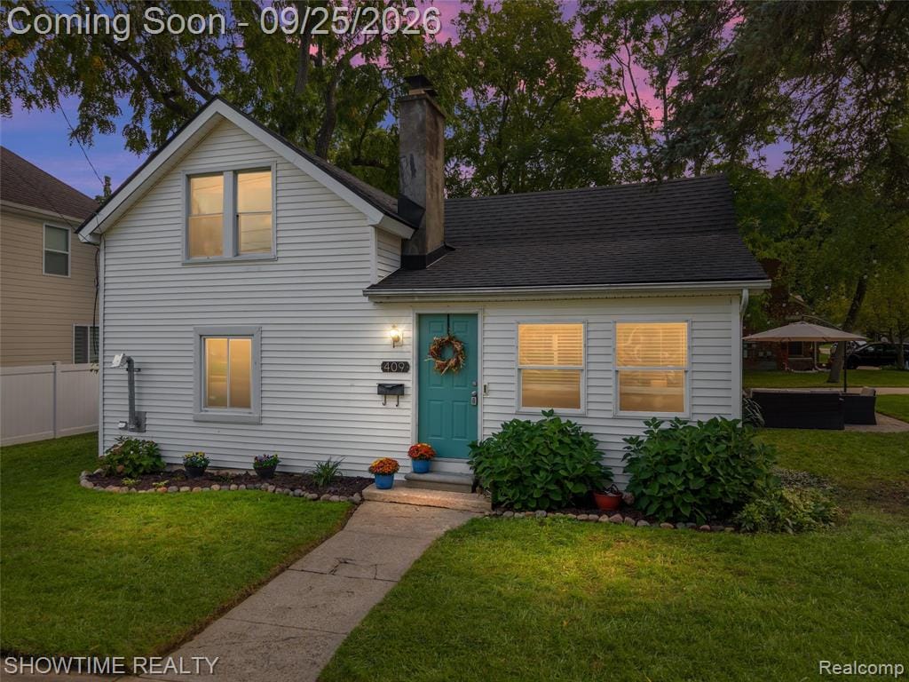 White siding exterior with a dark shingle roof, a prominent chimney, and a vibrant teal front door