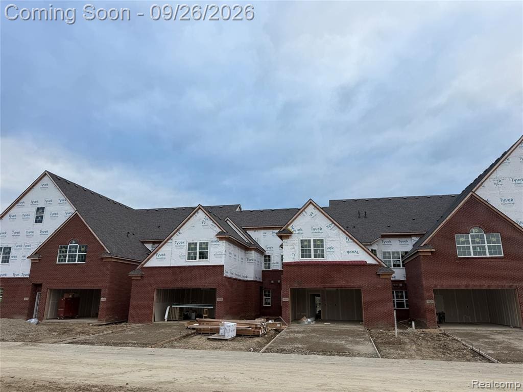 Brick exterior construction with multiple attached garage spaces and dark shingle roofing