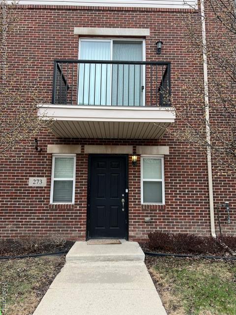 Brick exterior with a second-story balcony featuring black metal railings and a sliding glass door