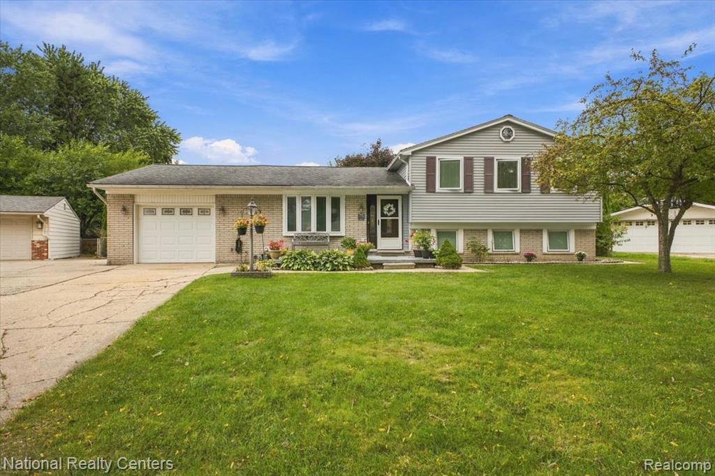 Split-level residence featuring a brick and siding exterior, attached two-car garage, and a bay window