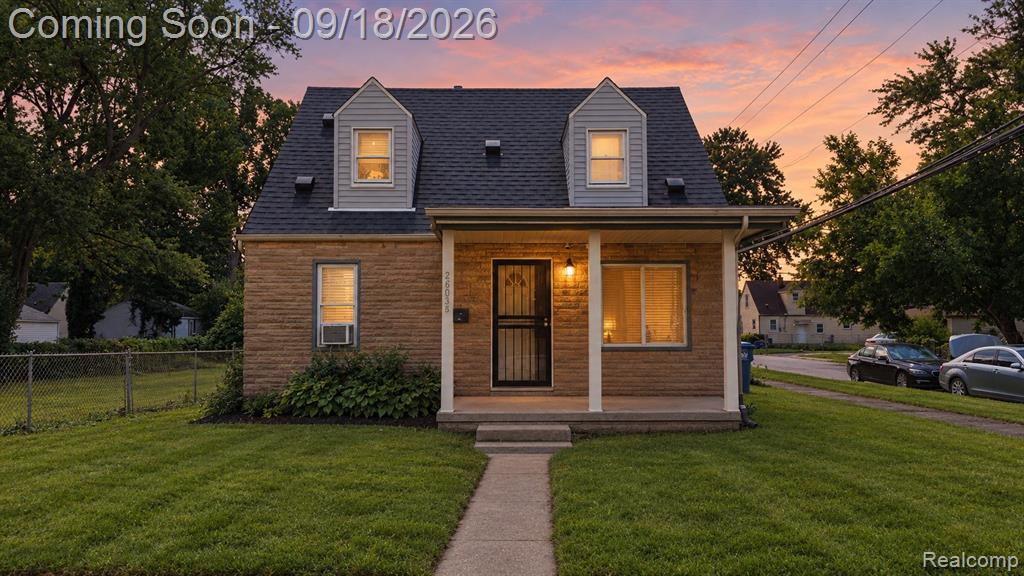 Gabled dormers, stone facade, covered front porch, and a concrete walkway