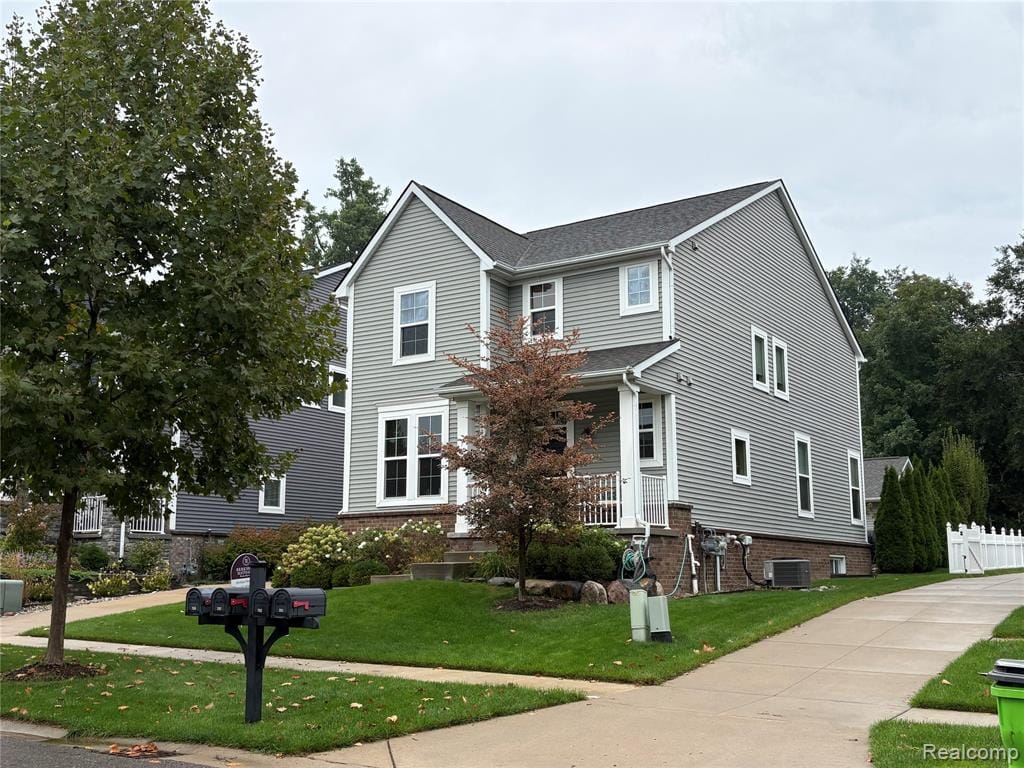 Gabled two-story residence with light gray horizontal siding, white trim windows, and a brick foundation