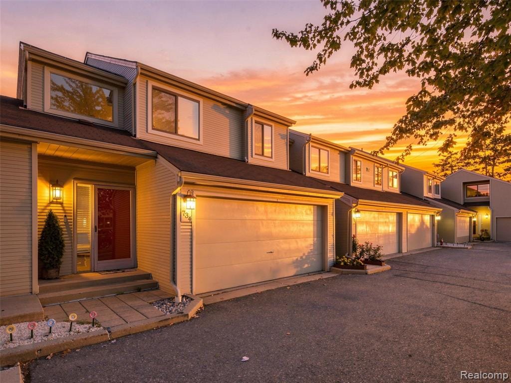 Light-colored siding exterior with a red entry door, an attached garage, and a concrete pathway