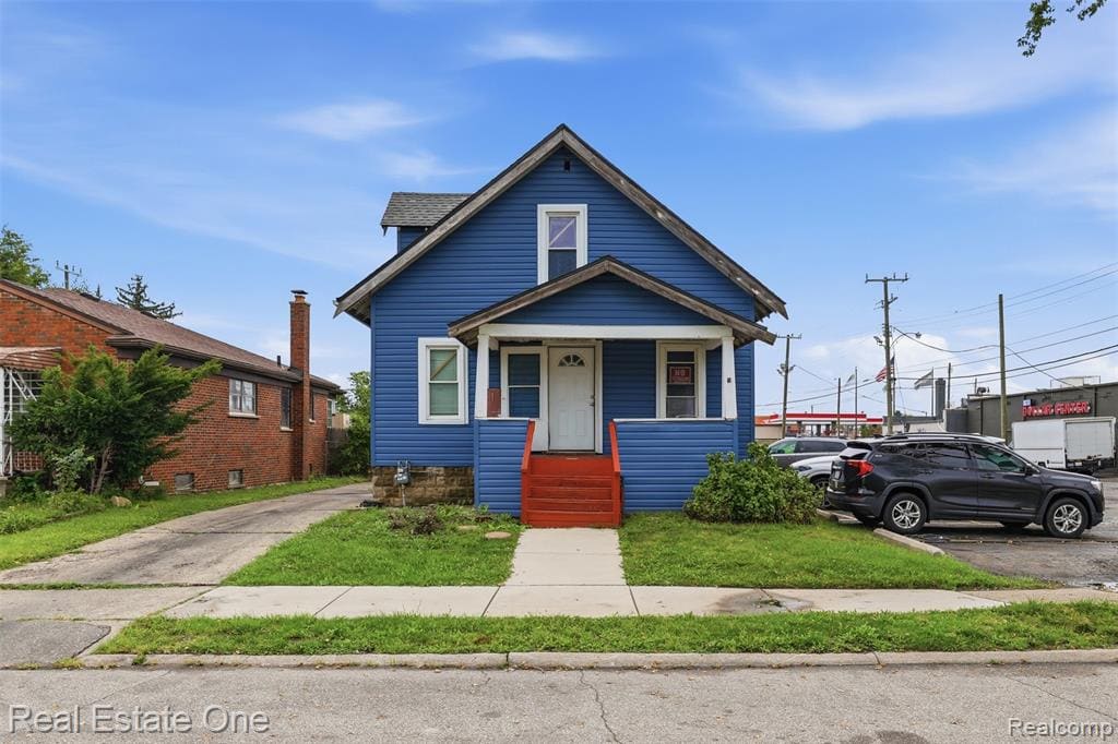 Blue siding exterior with red porch stairs, covered front entry, and a paved driveway