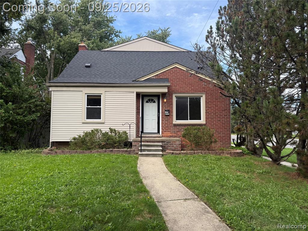 Brick and siding exterior with a dark shingle roof, featuring a light-colored entry door with an arched window, and a concrete pathway leading to stone steps