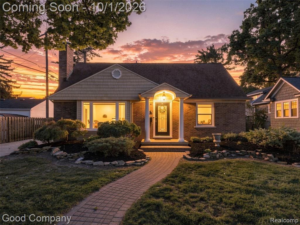 Charming brick residence showcasing a welcoming front entry with arched doorway, illuminated by warm overhead lighting