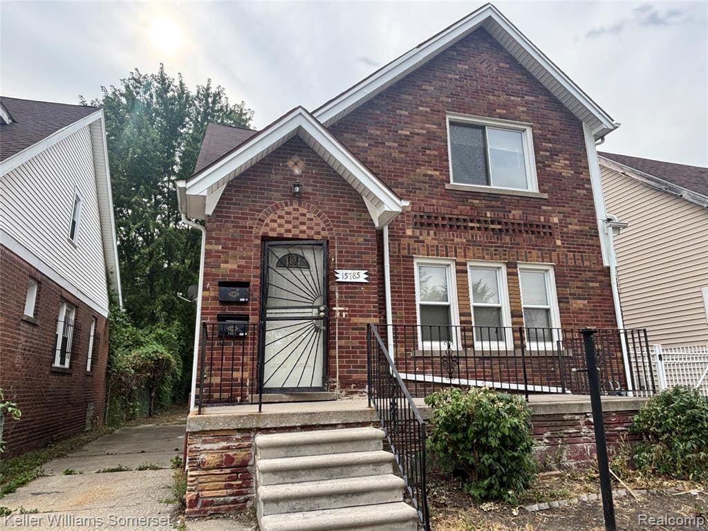 Charming brick two-story home featuring a welcoming front facade with arched entryway, decorative iron railings, and stepped concrete entrance