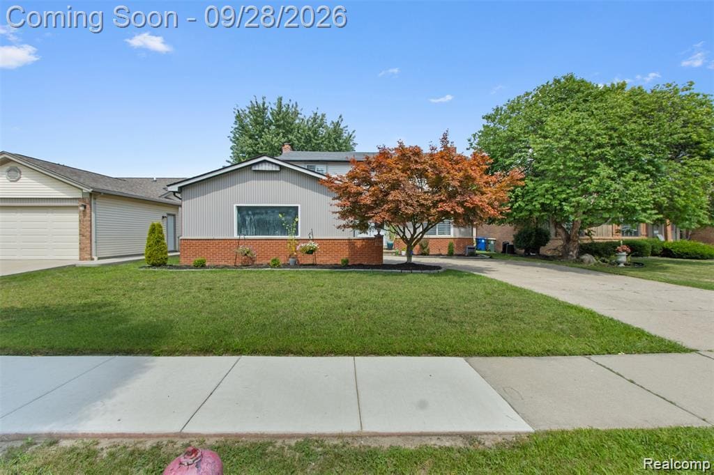 Gray siding and red brick exterior, attached garage, concrete driveway, and mature landscaping