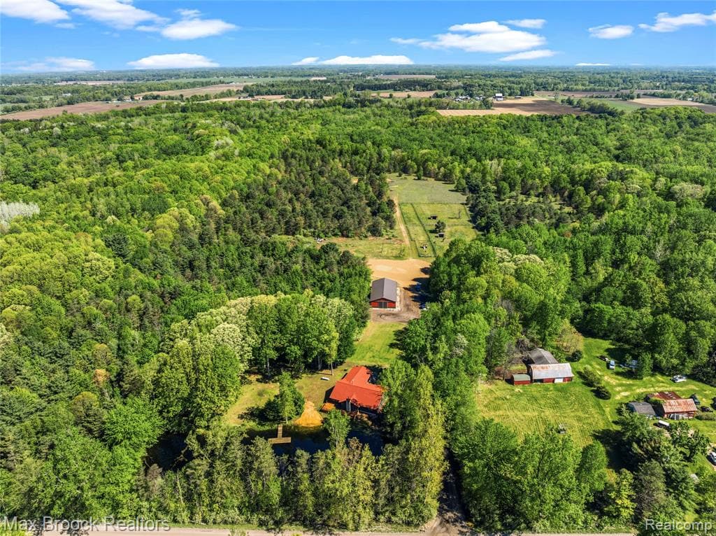 Hidden and tucked away, this is one of those properties that simply cannot be replicated. The sellers have lovingly cared for this 52-acre wooded paradise for years, and it shows everywhere you look. Towering trees, winding trails, a stocked pond with a sandy beach, and the Flint River weaving along the back of the property create a setting that feels like something straight out of a movie. Whether your dream is hunting, fishing, horseback riding, boating, raising livestock, or simply escaping the noise of everyday life, this property offers a lifestyle that's becoming harder and harder to find. The 3-bedroom, 3-bath home offers approximately 1,900 square feet with hardwood flooring throughout and a new roof in 2025. If homes had Carfax reports, this one would show clean, clean, clean—the owners have kept meticulous records of virtually everything ever done to the property. Outside, you'll find fenced pastures with shelters, electric and water at each pasture, a hay field, outdoor riding arena, miles of groomed trails, and a 40 x 80 pole barn with room for stalls, a tack room, and grain storage. The unfinished bonus 16 x 48 flex space in the second 30 x 40 barn is ready for your vision—whether that's additional hobby space, a guest suite, home office, apartment, or Airbnb. Bordering a 70-acre nature preserve, this is a place where kids can still catch fish, horses can roam, wildlife is abundant, and life slows down just enough to remind you what matters. Properties with this kind of beauty, privacy, and soul rarely come along. Same day showings/immediate occupancy. Award winning North Branch Schools.